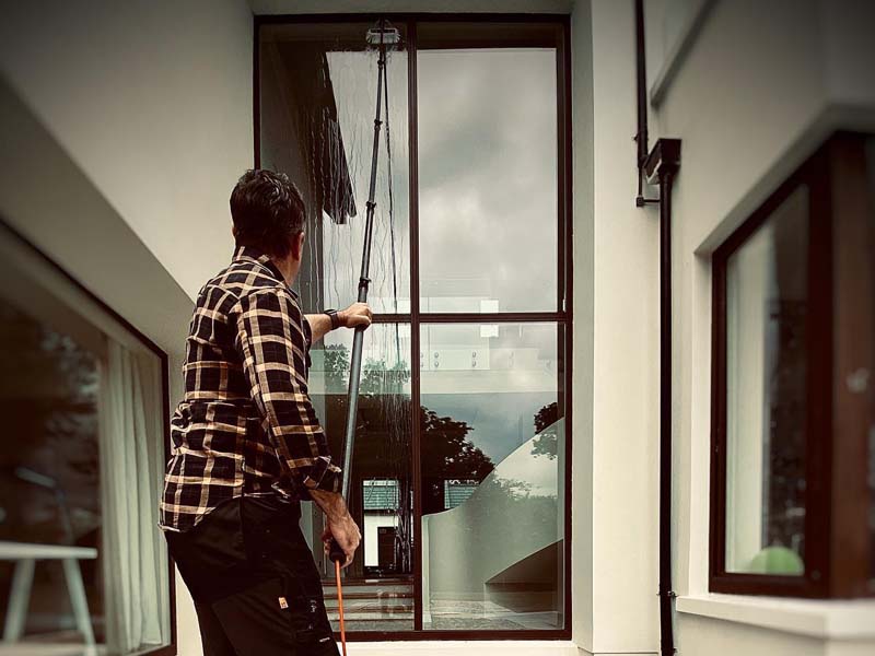 Window cleaner using a pole system to clean a large glass window
