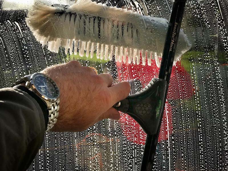 Close-up of a squeegee cleaning soapy glass