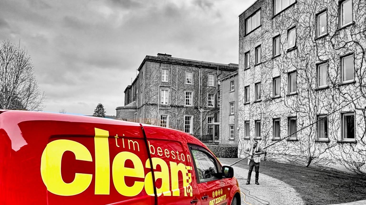 Tim Beeston Cleaning van in the foreground while a cleaner pole-washes the windows of a multi-storey building